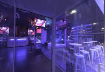 Eden Nightclub, a gay club in Torremolinos, Spain. Interior view with white tables, bar, and purple lighting. Gay travel destination.