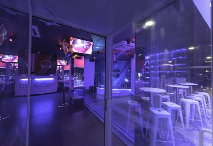 Eden Nightclub, a gay club in Torremolinos, Spain. Interior view with white tables, bar, and purple lighting. Gay travel destination.