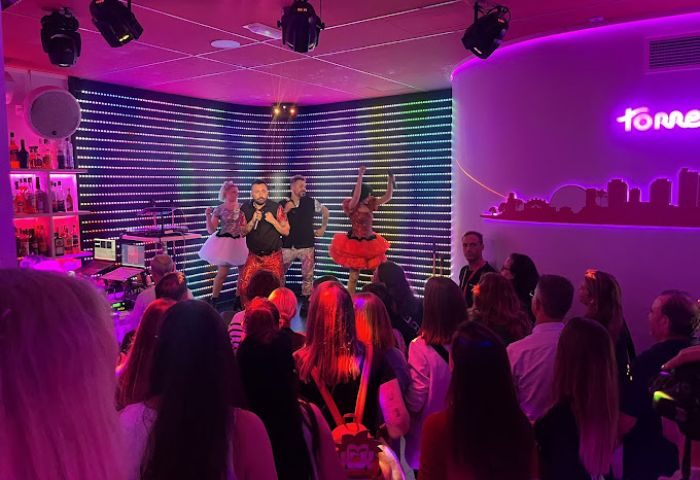 Crowd at Eden Nightclub, a gay club in Torremolinos, Spain. Performers on stage with neon lights. Gay travel destination.