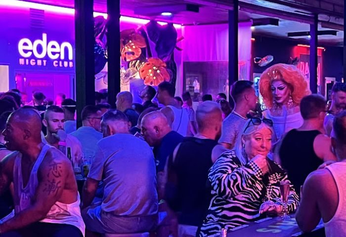 Eden Nightclub, a gay club in Torremolinos, Spain. Crowd of men, drag queen, and woman enjoy the nightlife. Purple lighting.
