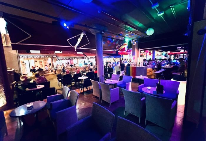 Eiffel Bar, a gay bar in Gran Canaria. Outdoor seating area with tables and chairs, rainbow bar, and colorful lighting.