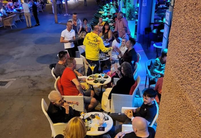 Eiffel Bar, a gay bar in Gran Canaria. People sit at tables outside, enjoying drinks. Nightlife scene, travel destination.