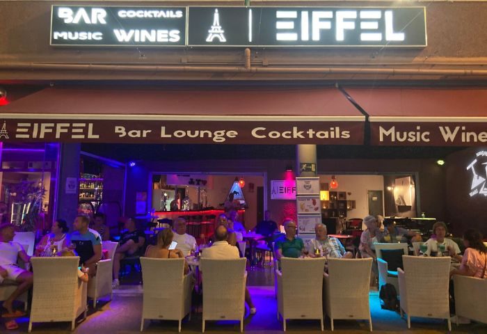 Eiffel Bar, a gay bar in Gran Canaria, Spain. People sit at tables outside the bar, enjoying drinks. Nightlife scene for gay men travelers.