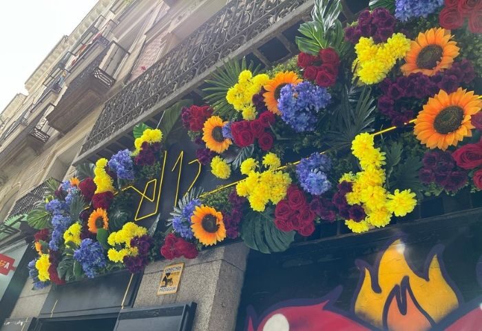 Entrance to El 12 Club, a gay bar in Madrid, Spain, adorned with colorful flowers. Gay travel destination with vibrant nightlife.