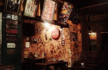 El Almacen Gay Bar interior in Mexico. Walls covered in posters, photos, and memorabilia. Cozy, dimly lit atmosphere. Gay travel destination.