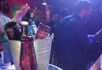El Almacen Gay Bar in Mexico: Bucket of beers on table, patrons enjoying the gay nightlife. Gay travel advice, gay bar scene.