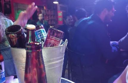 El Almacen Gay Bar in Mexico: Bucket of beers on table, patrons enjoying the gay nightlife. Gay travel advice, gay bar scene.