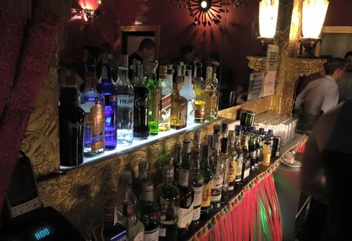 Bar at El Cangrejo, Eixample's gay bar in Barcelona. Bottles of liquor line the bar, with patrons in the background.