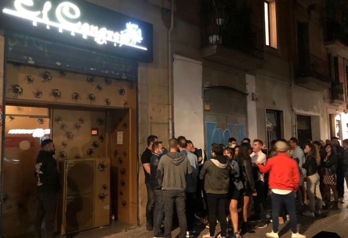 Night view of El Cangrejo gay bar in Barcelona's Eixample. A crowd of people are waiting in line to enter the popular gay venue.