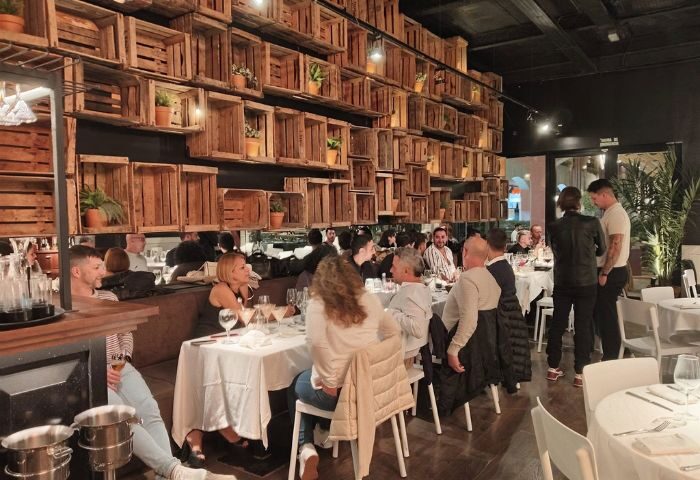 El Gato Lounge gay bar in Torremolinos, Spain. Interior view of the restaurant with people dining. Stylish decor with wooden crates on the wall.