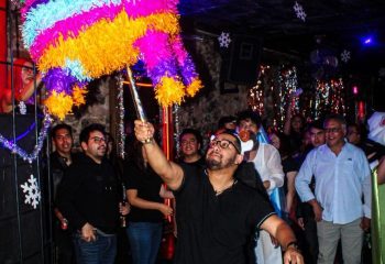 El Pecado Gay Bar in Mexico: A man swings a colorful piñata at a gay bar, surrounded by a crowd of people celebrating.