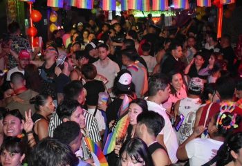 El Pecado Gay Bar in Mexico: A crowded scene with many people, rainbow flags, and balloons. Nightlife for gay men's travel advice.