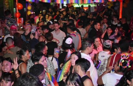 El Pecado Gay Bar in Mexico: A crowded scene with many people, rainbow flags, and balloons. Nightlife for gay men's travel advice.