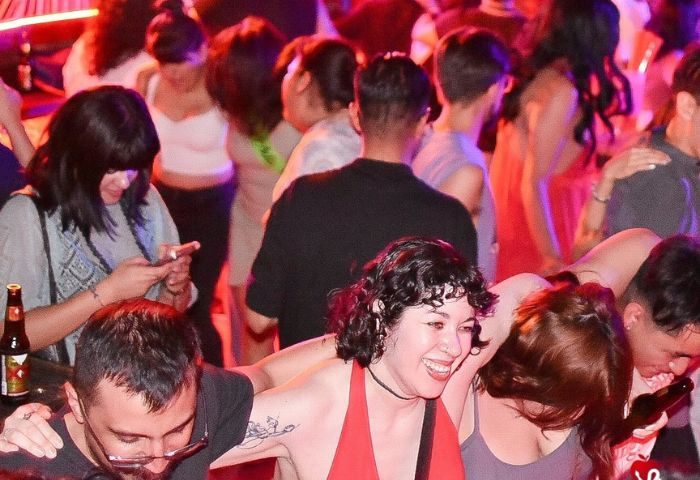 Crowd at El Pecado Gay Bar in Mexico. People dancing, drinking, and using smartphones. Nightlife scene, gay travel advice.