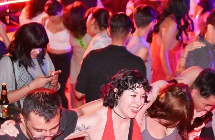 Crowd at El Pecado Gay Bar in Mexico. People dancing, drinking, and using smartphones. Nightlife scene, gay travel advice.