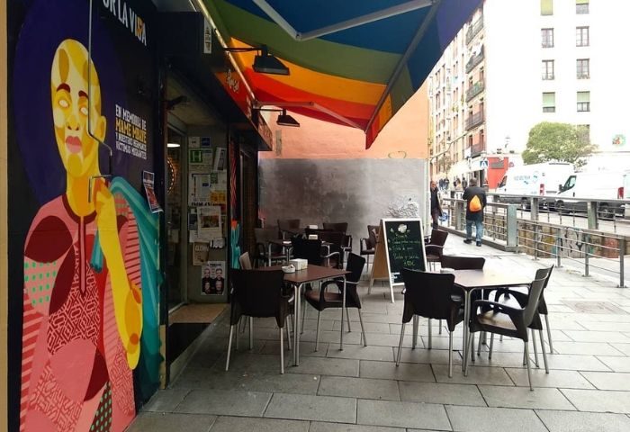 El Rincon Guay Gay Bar in Madrid. Outdoor seating area with rainbow awning. Mural on the wall. Gay travel advice.