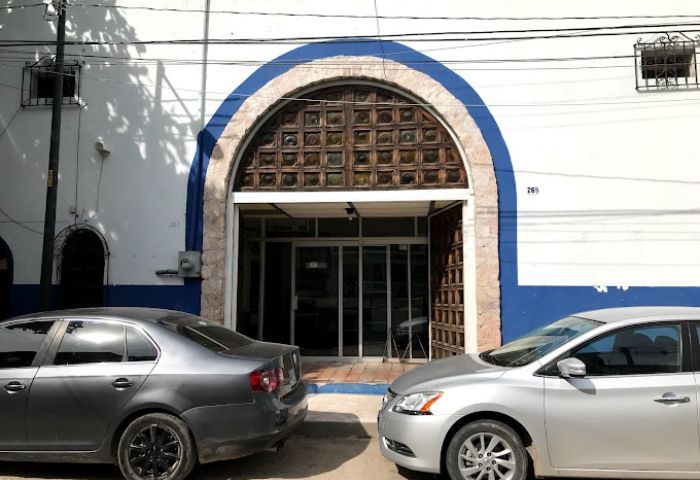Elizabeth Taylor Theater, Puerto Vallarta. Building with arched doorway, blue trim, and two cars parked in front. Gay cruising spot.
