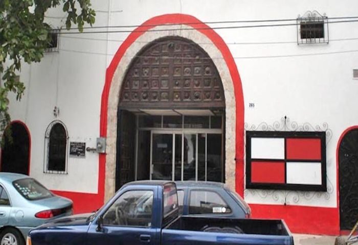 Elizabeth Taylor Theater, Puerto Vallarta. White building with red trim, arched doorway, and cars parked in front. Gay cruising spot.