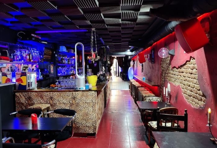 Interior of Elvira Cafe, a gay bar in Barcelona. Leopard print bar, red walls, and blue lighting create a vibrant atmosphere.