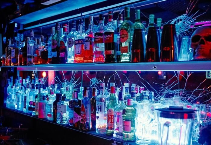 Elvira Cafe Gay Bar in Barcelona: Liquor bottles on shelves, illuminated with blue light. Skull decor. Gay travel destination nightlife.