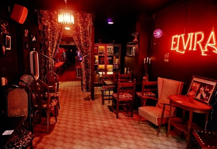 Interior of Elvira Cafe, a gay bar in Barcelona. Red lighting, eclectic decor, and vintage furniture create a unique, inviting atmosphere.