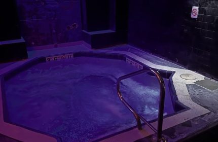 Entourage Las Vegas gay cruising: A dark, indoor hot tub with purple lighting & a metal handrail. No smoking sign visible on the wall.