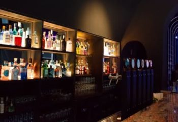 Euforia Bar Milan interior. Shelves stocked with liquor bottles, beer taps. Gay bar scene, nightlife. Milan travel advice.