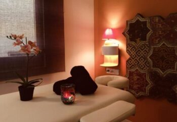Gay Massage in Barcelona: Massage table with flower pot, towels, candle, lamp, and decorative screen. Eugenio provides massage.