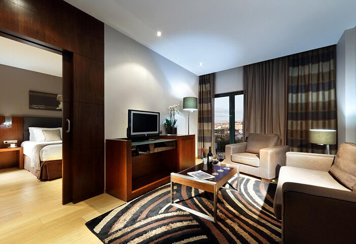 Eurostars Hotel das Letras, Lisbon. Luxury suite with living area, TV, wine, and city view. Ideal gay travel accommodations in Lisbon.