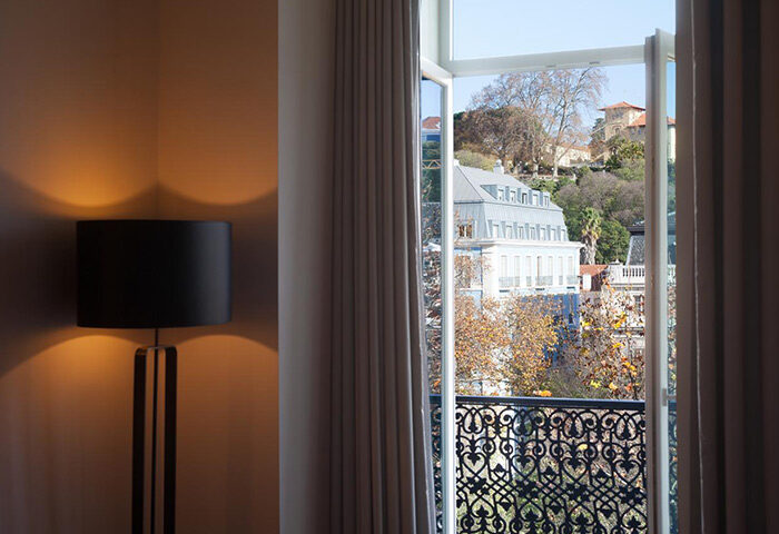 BessaHotel Liberdade view. Lisbon location: Room interior with lamp, balcony, and city view. Gay-friendly hotel in Lisbon, Portugal.