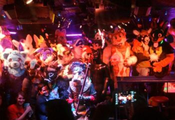 Executive Suite Events: Furries gather, posing in colorful animal costumes. A person takes a photo at this gay travel event.