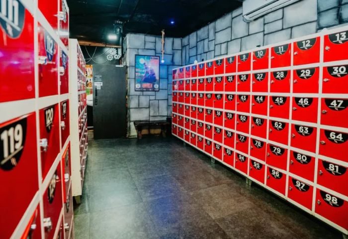 Lockers at Exxxtreme Cruising Club, a gay cruise club. Red lockers line the wall. A bench sits near a door. Gay travel advice.