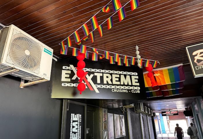 Entrance to Exxxtreme Cruising Club, a gay cruise club. Rainbow flags decorate the ceiling. Gay travel advice.