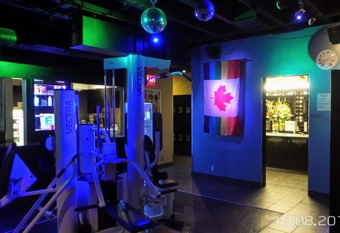 Steamworks Gym in Vancouver: Gay sauna's gym area with Vectra machines, disco balls, and a Canadian flag with rainbow stripes.