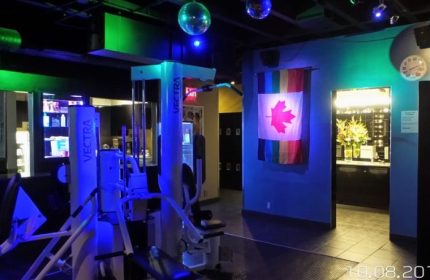 Steamworks Gym in Vancouver: Gay sauna's gym area with Vectra machines, disco balls, and a Canadian flag with rainbow stripes.