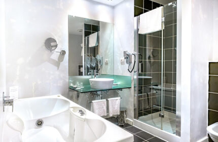 Hotel Leonardo Prague luxury bathroom. Find last minute gay hotels in Prague Old Town city center. Bathtub, shower, sink, and mirror.