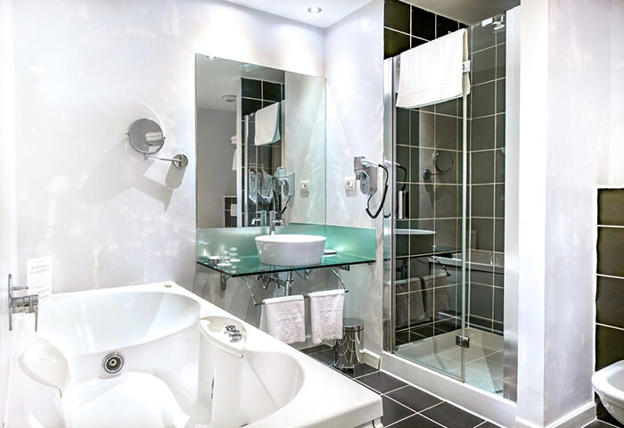 Hotel Leonardo Prague luxury bathroom. Find last minute gay hotels in Prague Old Town city center. Bathtub, shower, sink, and mirror.