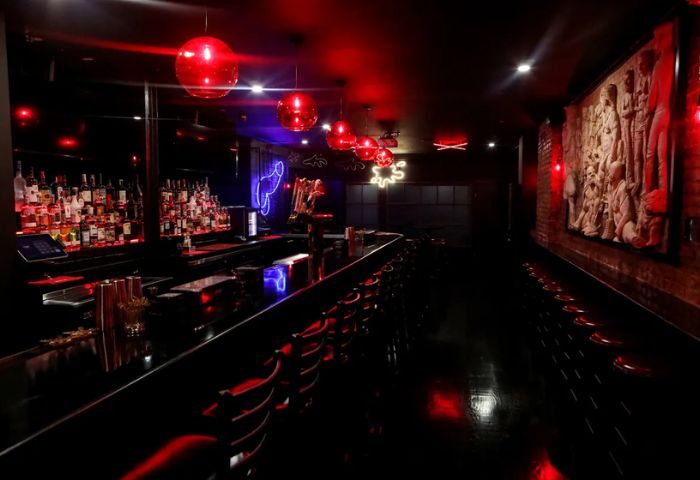 Interior of FLEX Gay Bar in New York. Red lighting, bar stools, bottles, and neon decorations create a vibrant atmosphere for gay men.