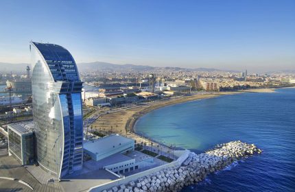W Barcelona, a famous gay-friendly hotel. Aerial view of the iconic hotel by the sea, Barcelona cityscape in the background.
