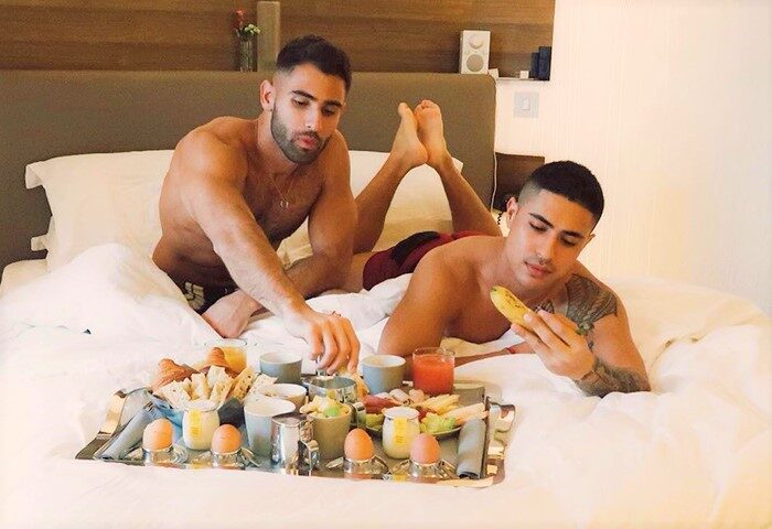 Gay men's travel: Two shirtless men in bed with breakfast at Hôtel Jules & Jim, a famous adults-only gay hotel in Paris.
