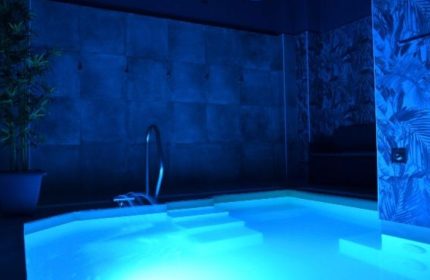 Fenix Sauna Milano: Blue-lit jacuzzi, steps, and handrail. Gay sauna travel advice. Relaxing spa experience.