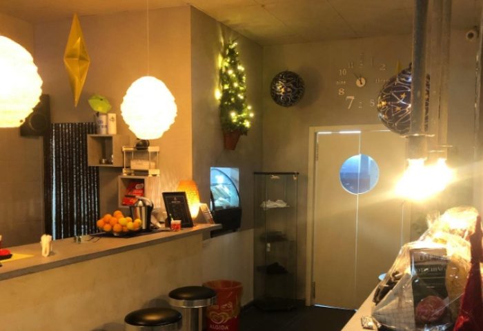 Fenix Sauna Milano interior. Bar area with stools, counter with fruit, and decorative lighting. Gay sauna travel advice.