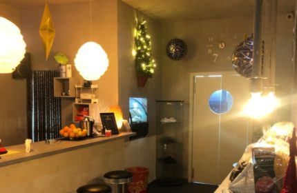 Fenix Sauna Milano interior. Bar area with stools, counter with fruit, and decorative lighting. Gay sauna travel advice.
