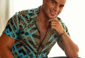 Fernando Ferraz, gay masseur in Central London. Smiling man in patterned shirt, gold watch and bracelet. Gay massage spa services.
