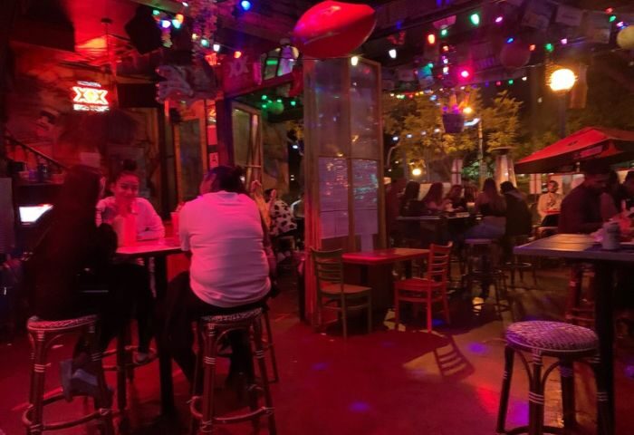Fiesta Cantina bar with colorful lights. People sit at tables in the outdoor area. Gay bar travel advice.
