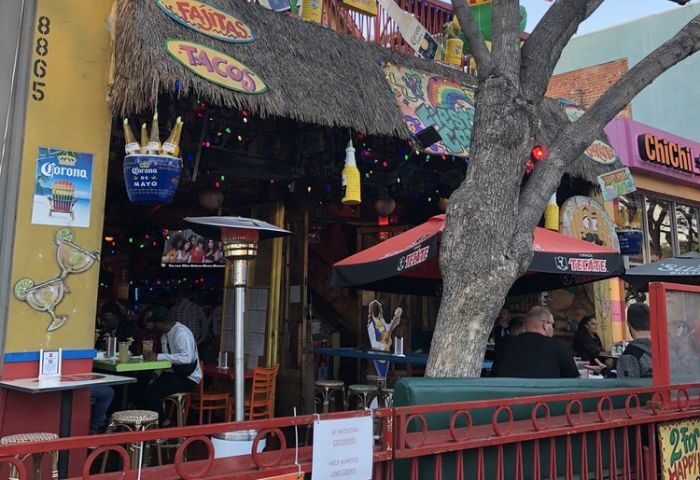 Outdoor view of Fiesta Cantina, a gay-friendly restaurant. The facade features a thatched roof, colorful decorations, and outdoor seating.