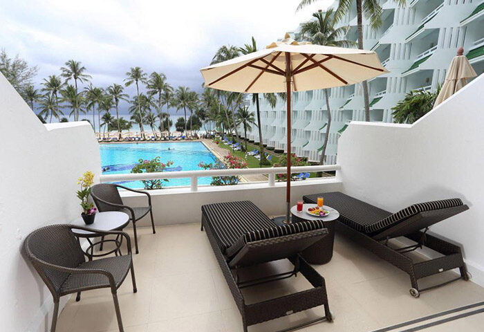 Le Meridien Phuket Beach Resort balcony view. Beachfront luxury gay honeymoon hotel with pool, lounge chairs, and ocean view.