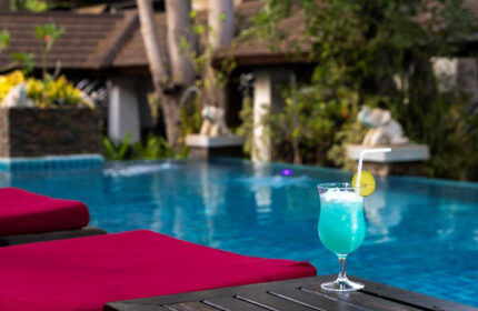 Samed Pavilion Resort beachfront pool view with a blue cocktail. Find a cheap gay hotel in Koh Samet now for your next vacation.
