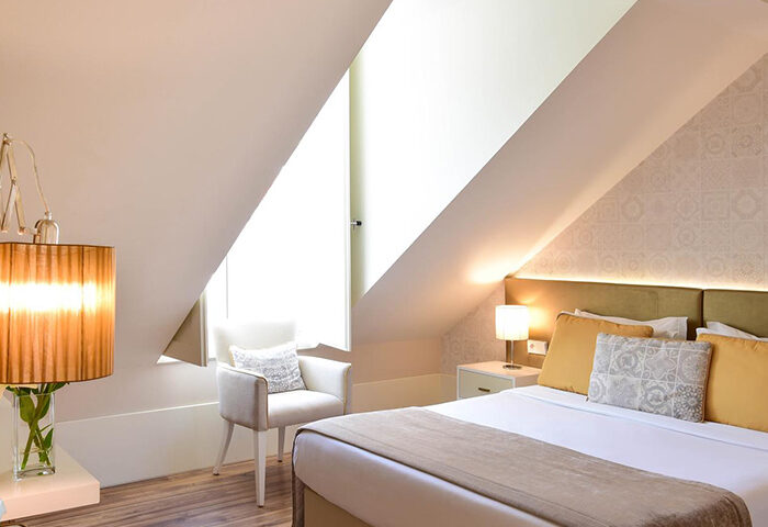 My Story Hotel Ouro room, Lisbon. Cheap gay hotel in main tourist area. Attic room with bed, chair, lamp, and angled ceiling.