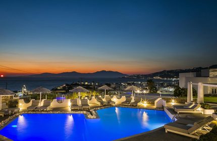 Ilio Maris hotel pool in Mykonos Town at sunset. Luxury gay honeymoon hotels offer stunning views. Perfect for LGBTQ+ travel & relaxation.